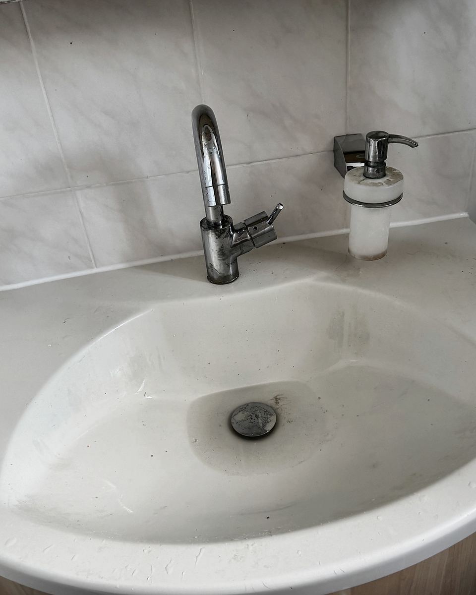 Waschtisch vor der Reinigung mit Flecken und Ablagerungen am Abfluss